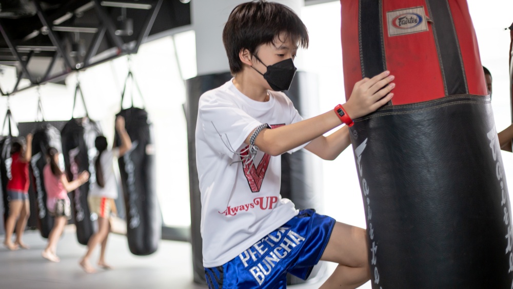 muay thai student doing heavy bag in kids class